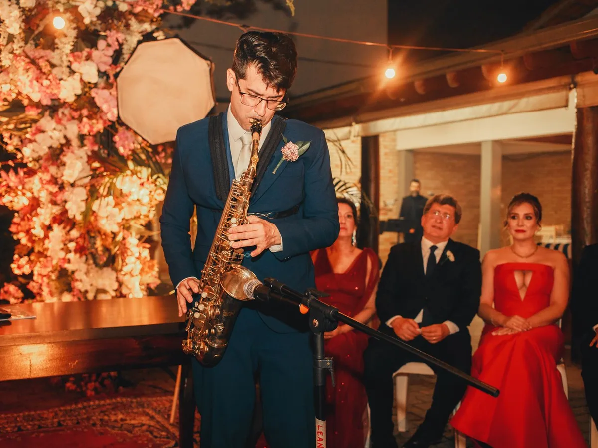 Saxophonist im blauen Anzug spielt bei einer Trauung, dahinter sitzen Gäste in Abendgarderobe