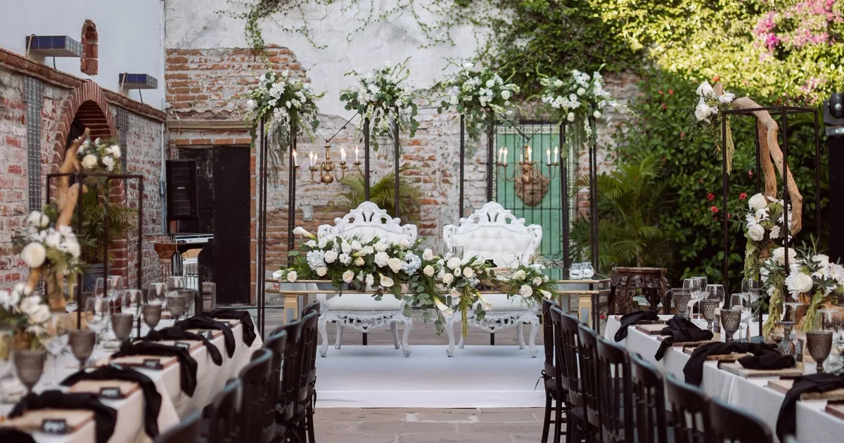 Festlich gedeckte Hochzeitstafeln im begrünten Innenhof einer Hochzeitslocation