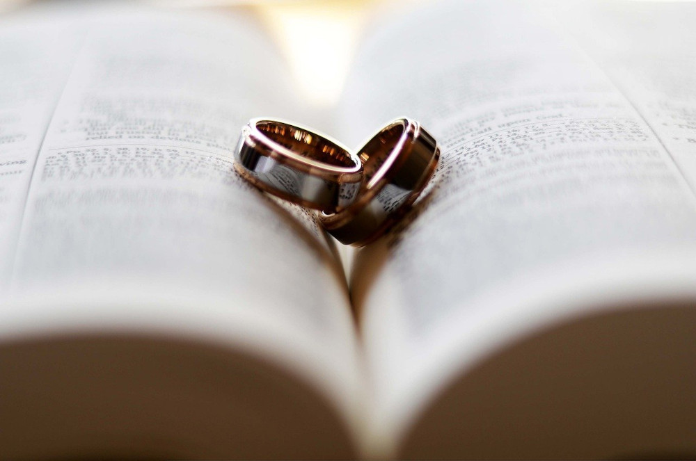 Hochzeitstage-Rechner: Zwei Eheringe liegen auf einem Buch
