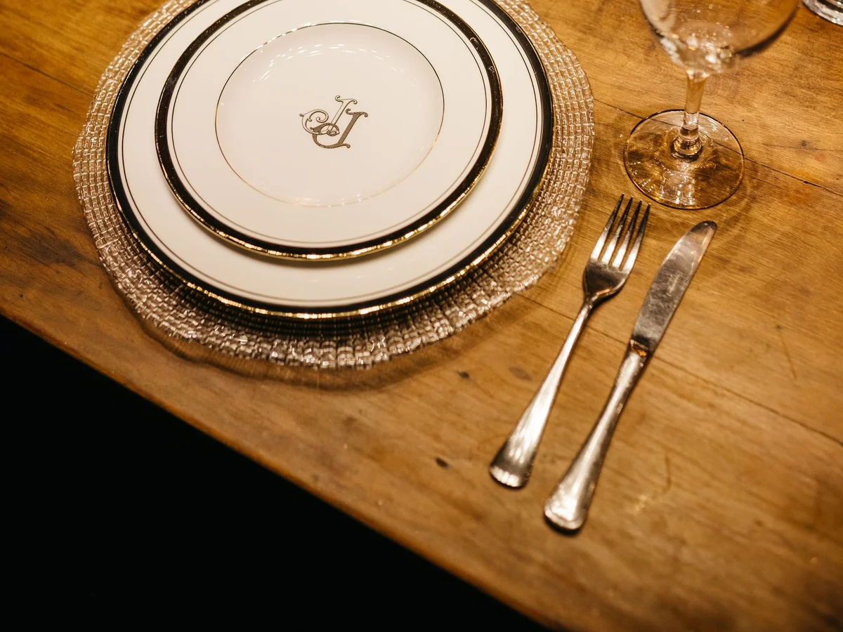 Festlich gedeckter Tisch mit goldberandetem Porzellan, Besteck und Weinglas