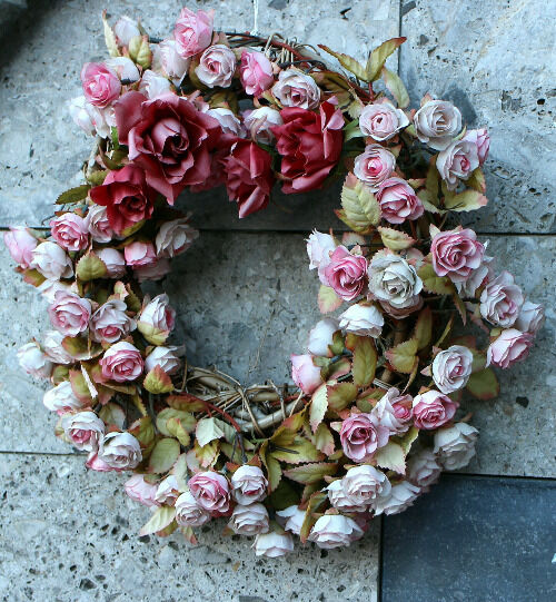 Ein Rosenkranz liegt auf dem Boden und ist mit pinken Rosen dekoriert