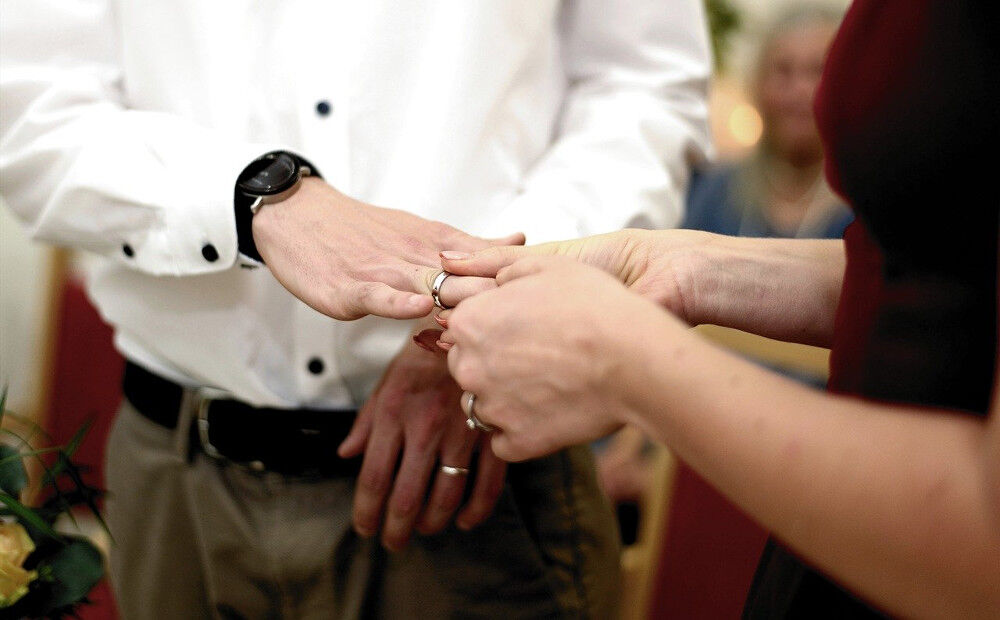 Ein goldener Ehering wird von der Braut auf den Finger des Bräutigams geschoben