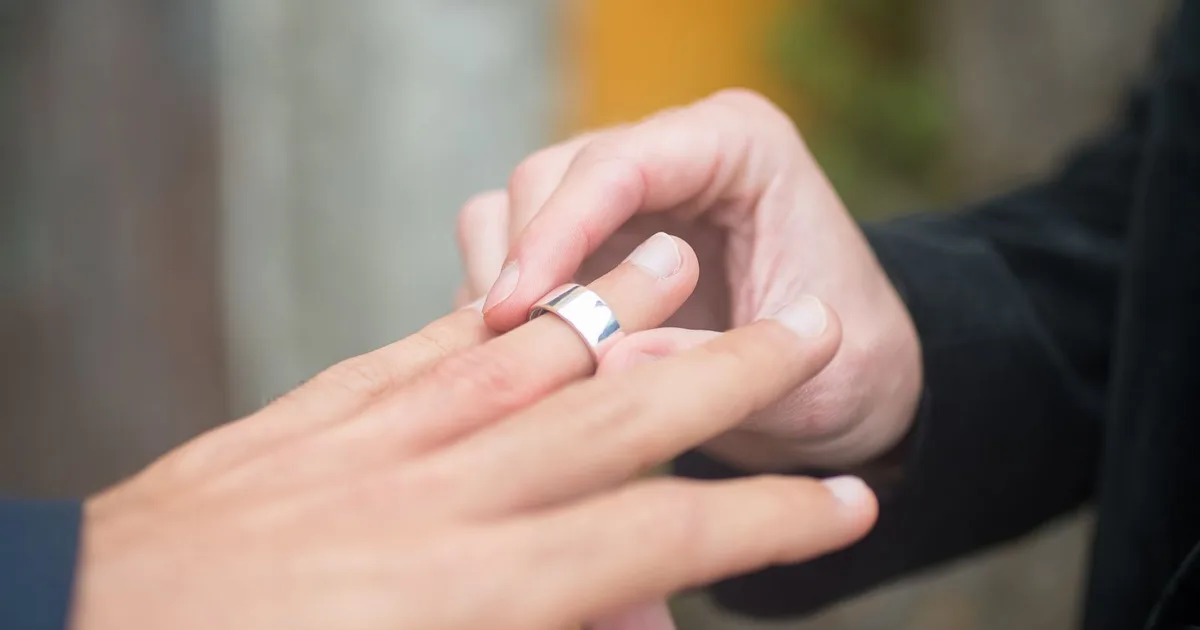 Ein Partner steckt dem anderen bei der Trauung den Ehering an den Finger
