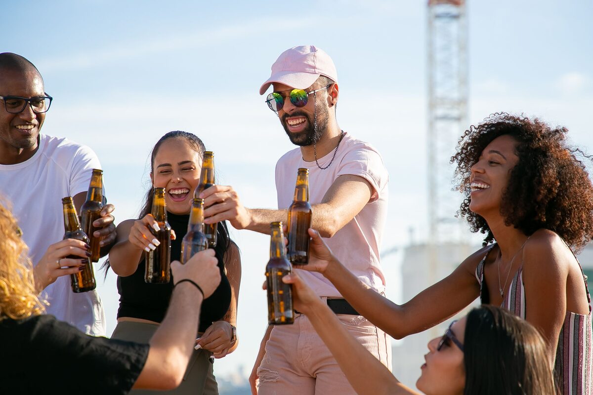 Freunde stoßen bei einer Feier im Freien mit Bierflaschen an