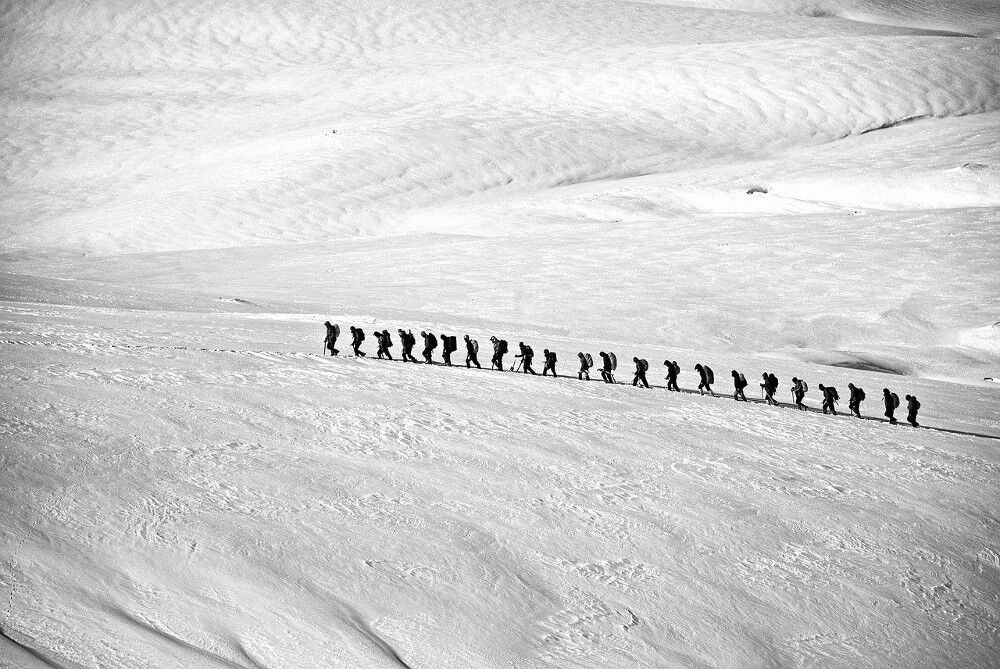 Riesige Schneelandschaft auf einem Berg mit mehreren Wanderern, die Ski tragen