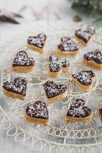 Kekse in Herzform mit Schokolade und weißen Streuseln überzogen
