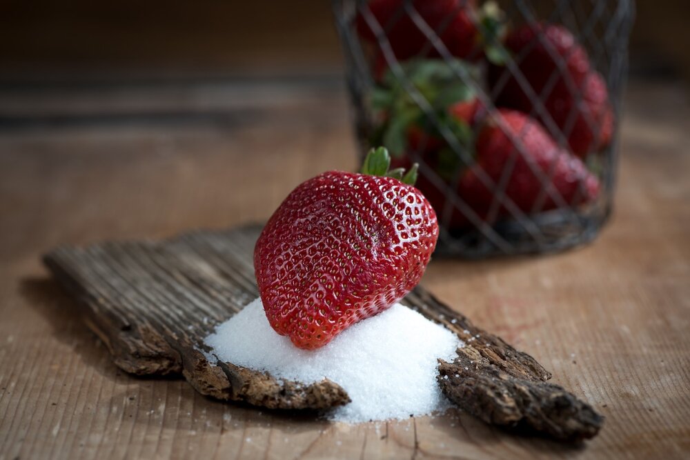 Eine Erdbeere liegt auf einem kleinen Häufchen Zucker