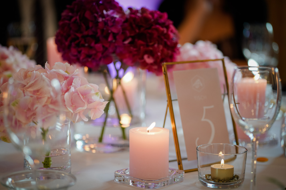 Pinke Hochzeitsdekoration steht auf einem Tisch mit Nummernkärtchen