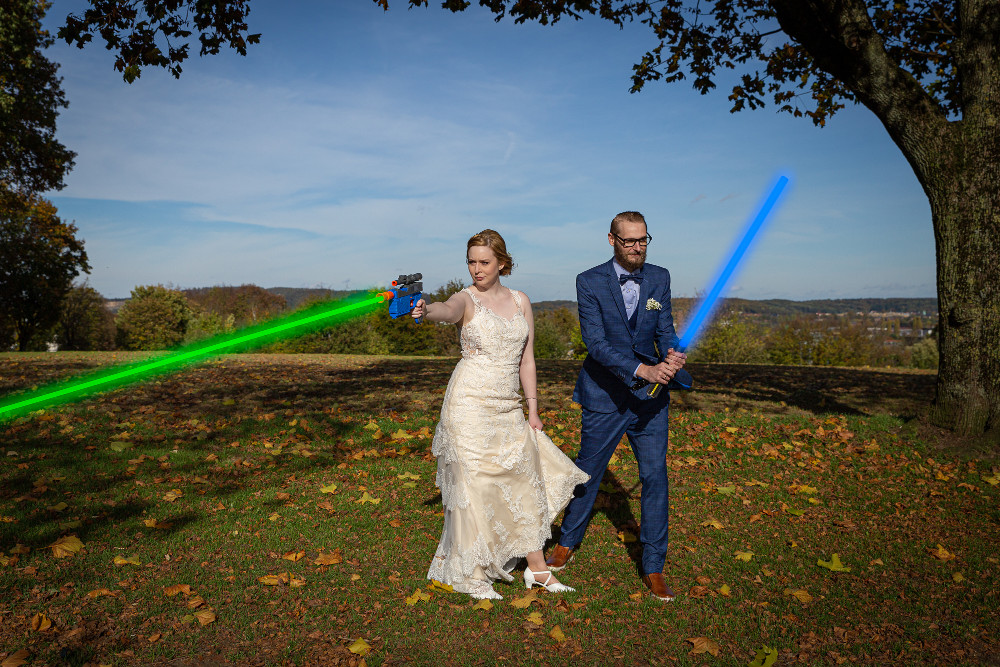 Bräutigam hält ein Laserschwert und die Frau eine Pistole, die Laser verschießt