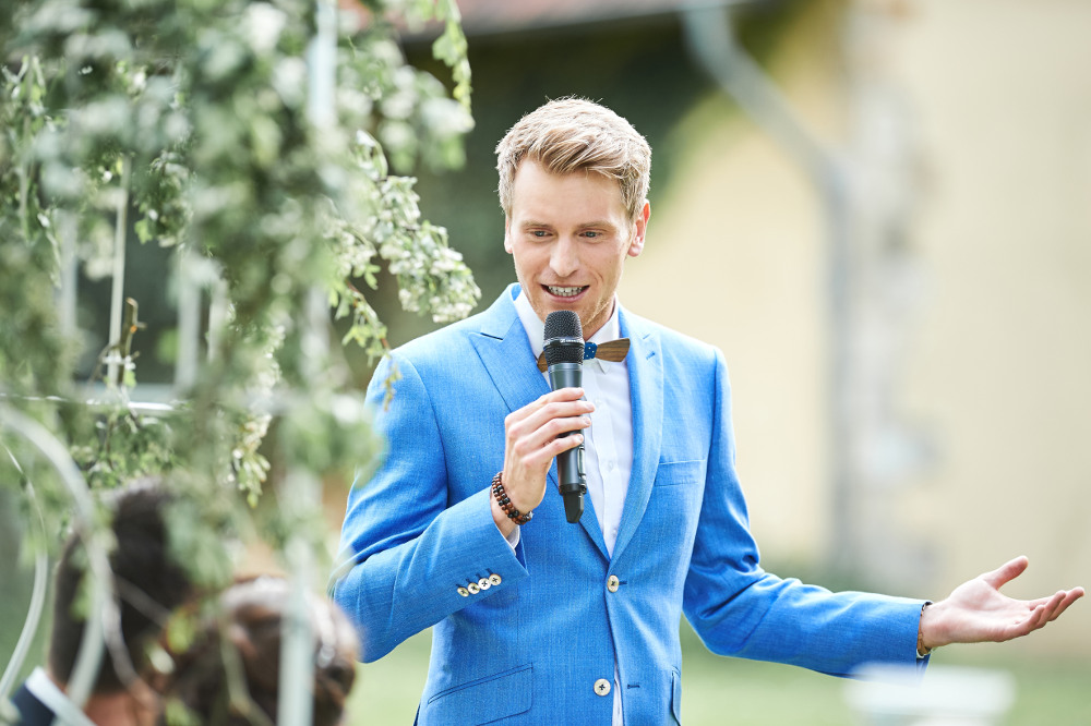 Der Moderator trägt einen blauen Anzug und moderiert die Hochzeit
