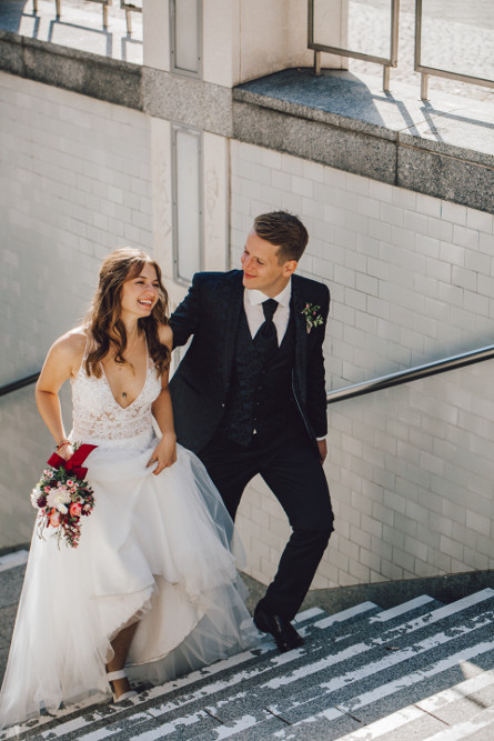 Bräutigam schaut die Braut verliebt an und geht mit ihr die Treppe hoch