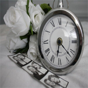 Kategorie Erinnerung: Silberne Taschenuhr neben einem Fotostreifen und weißen Rosen