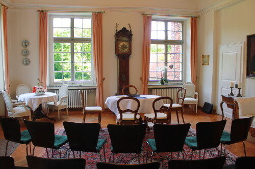 Trauzimmer mit antiker Standuhr und Tisch für das Brautpaar und den Standesbeamten. Zusätzlich weitere Stühle für die Hochzeitsgäste