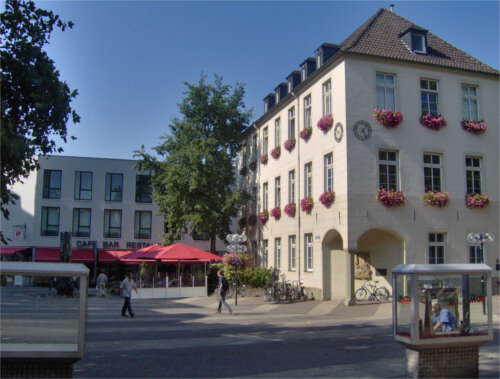 Altes Rathaus von Rheine in der Neuzeit: Auf der linken Seite befindet sich ein Cafe und auf der rechten Seite das besche Rathaus mit klassischen Rechteckfenstern